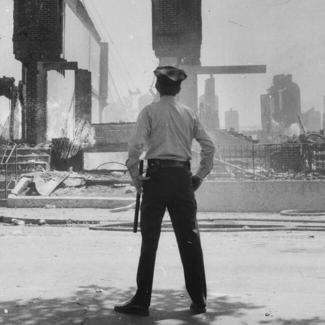 A Philadelphia police officer observes the rubble after the MOVE bombings