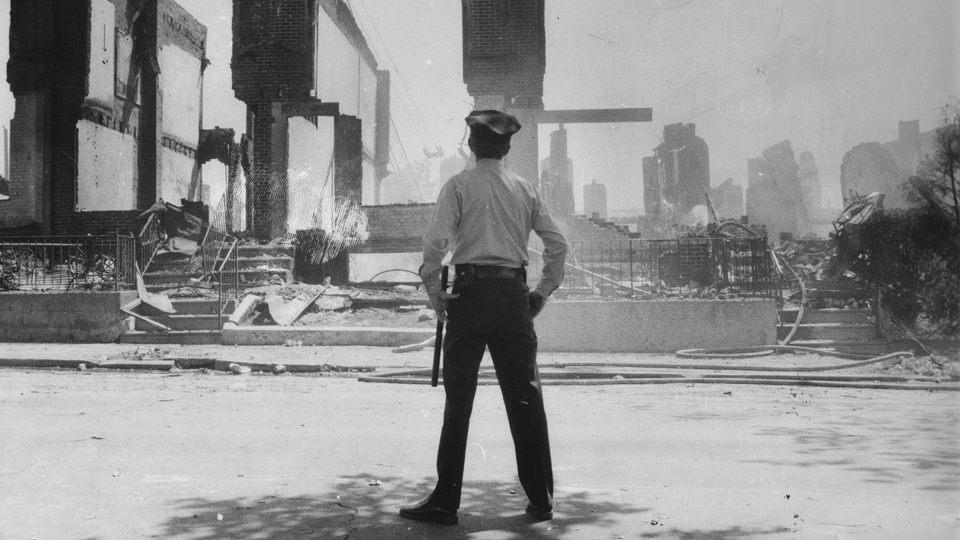 A Philadelphia police officer observes the rubble after the MOVE bombings