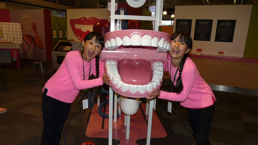 Twin Sisters Mia and Alexandra in a museum with giant wind-up teeth.