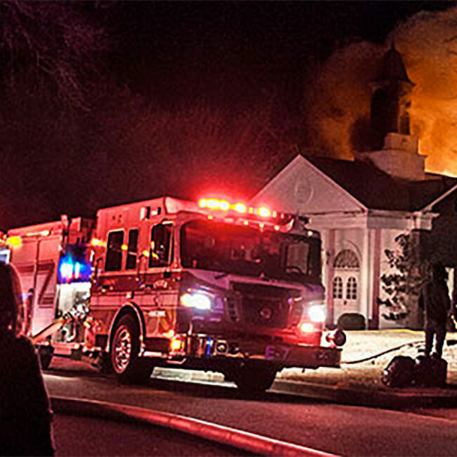 Emergency response vehicle with flashing lights parked outside burning East Texas church.