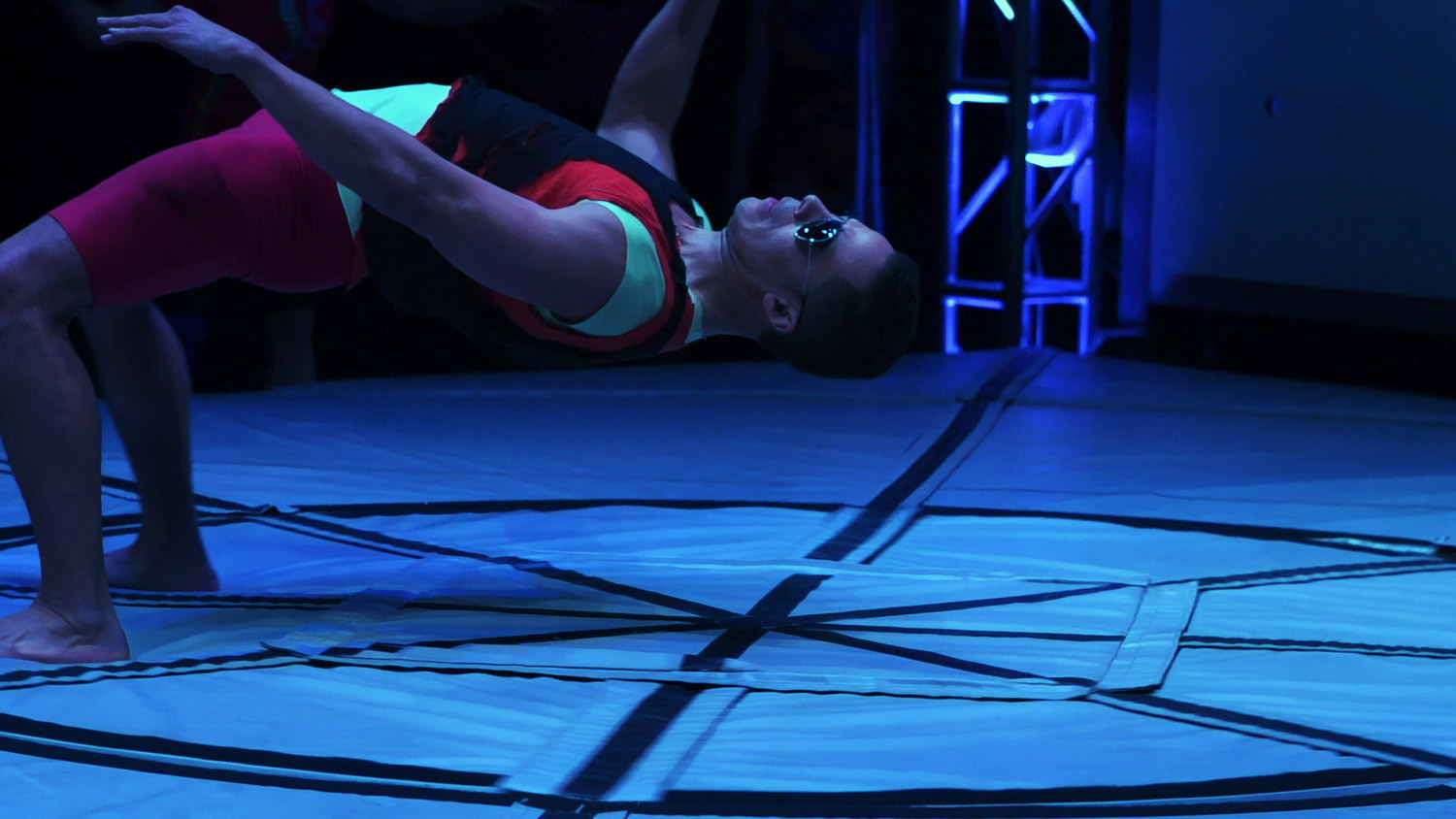 Dancer bends over backwards on a spinning floor to keep his balance.