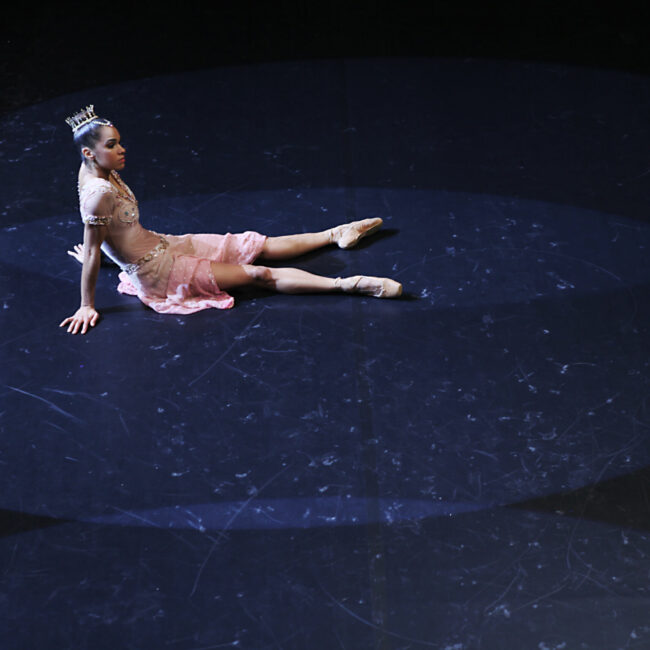 Misty Copeland sitting on stage in costume and shoes on