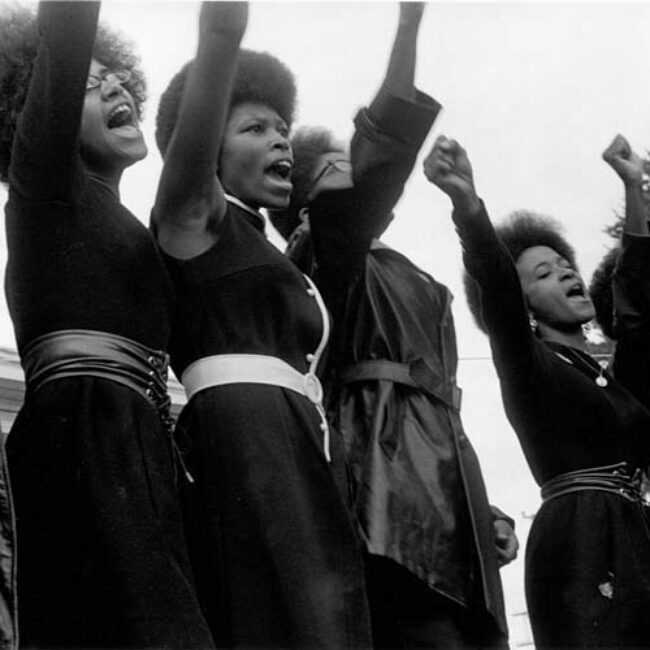 Woman dressed in all black with right fists in the air