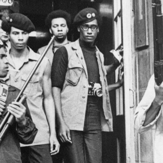 Black Panthers exiting building armed with rifles.