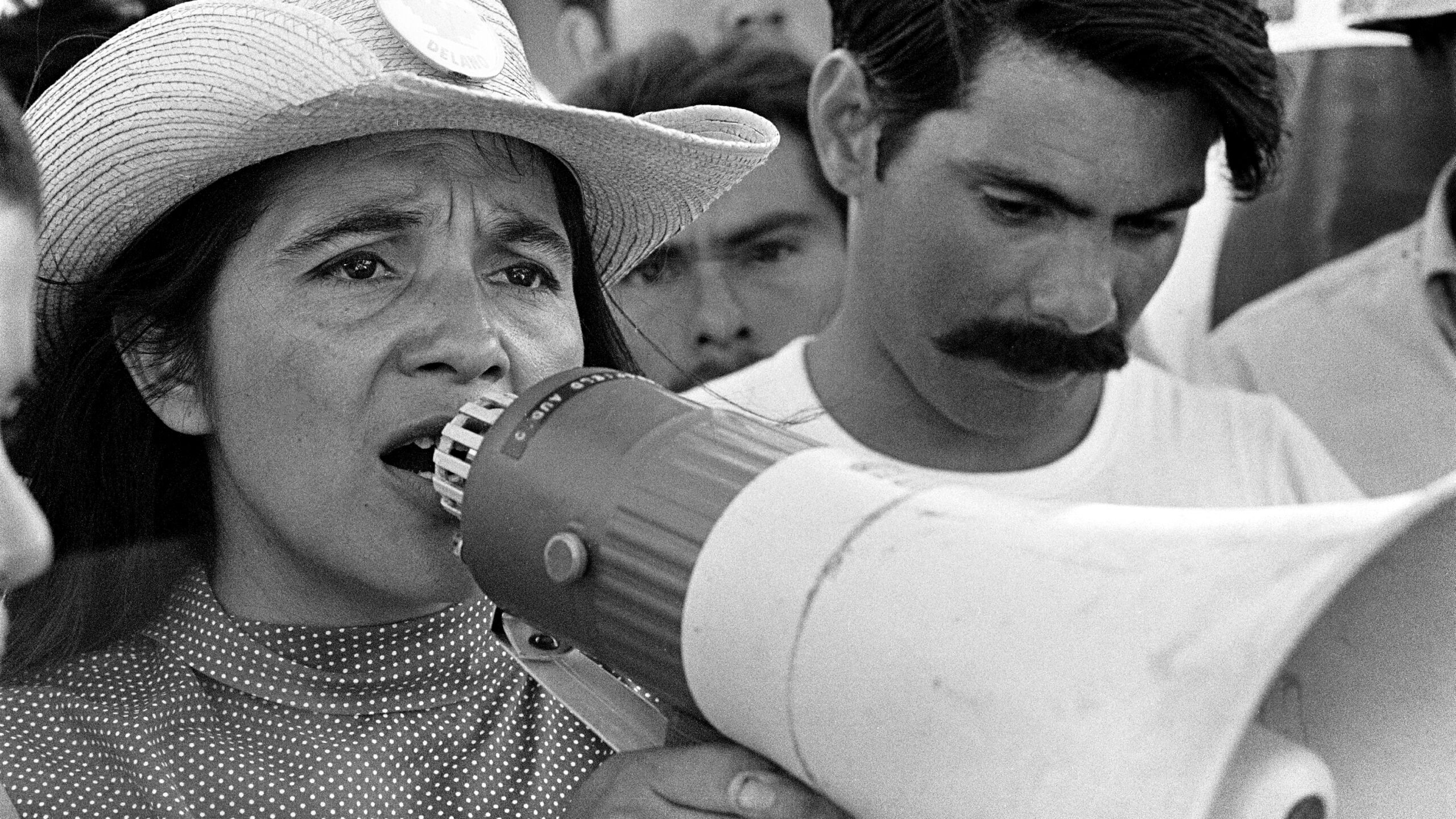 Dolores Huerta talking into megaphone while in a crowd