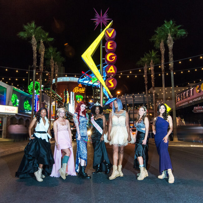 The women of Served Like a Girl dressed in pageant dresses with combat boots, on Vegas strip at night
