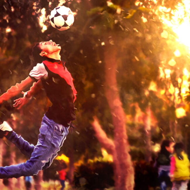 Man leaping while heading a soccer ball, in a park; creative commons image via PixaBay