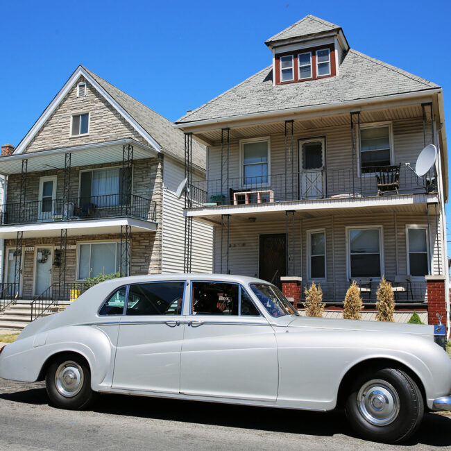 Elvis Presley's Rolls-Royce parks in front of a row house, in The King