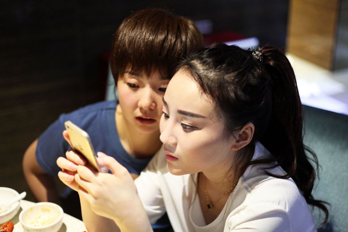 Shen Man and Dabao looking at live streaming on a phone, in People's Republic of Desire