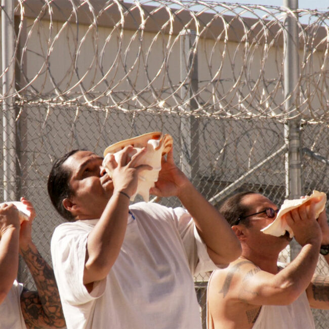 Native Hawaiian prisoners perform a ritual ceremony using conch shells as instruments