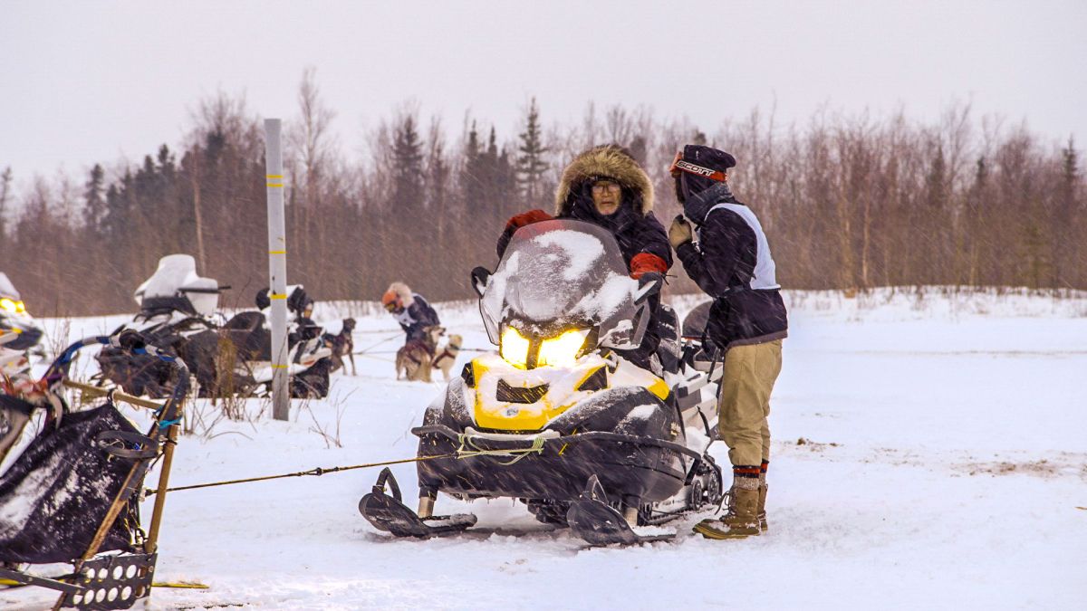 An elderly George Attla rides a snowmobile