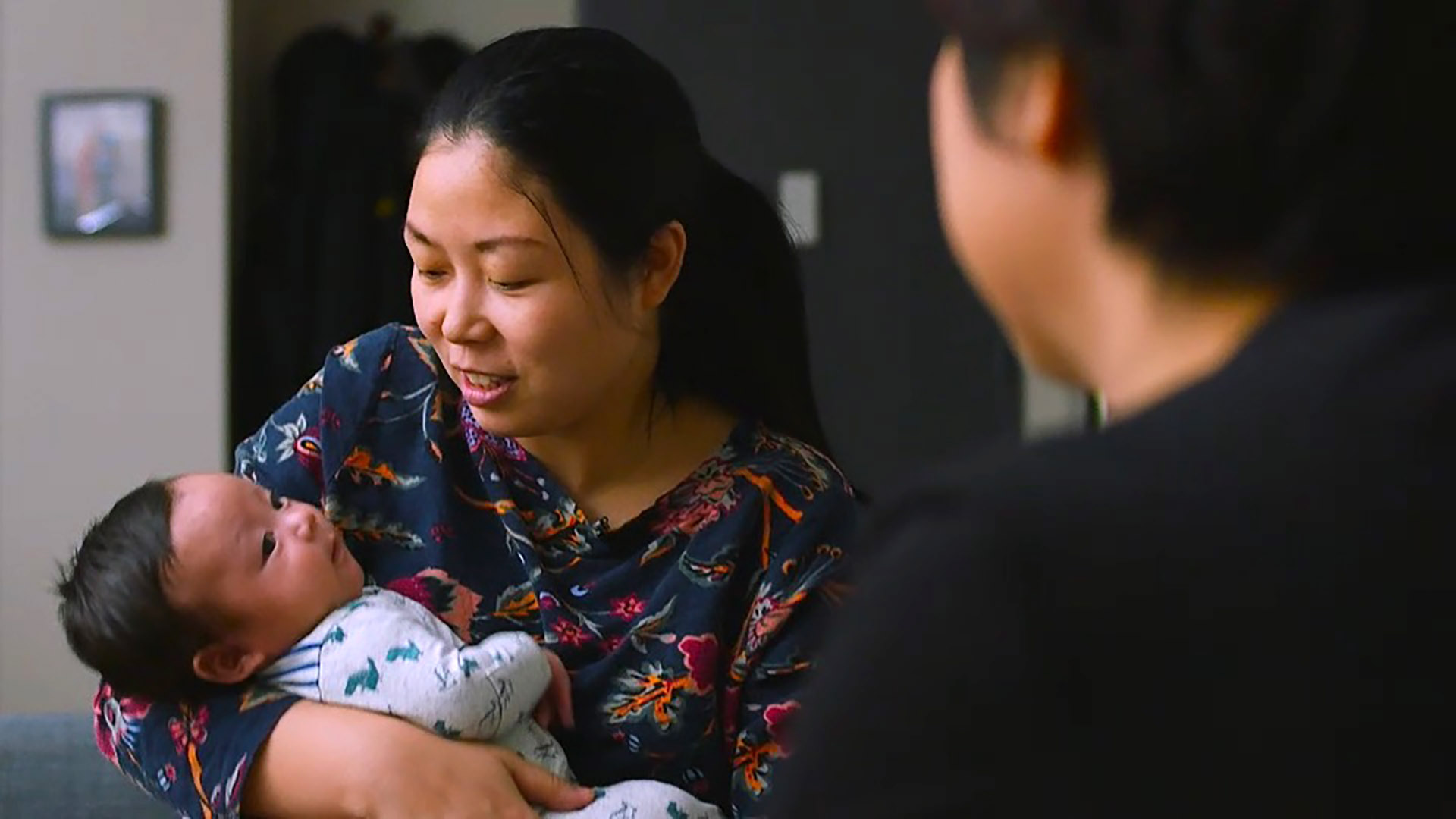 Nanfu wang holds her baby while interviewing her mother