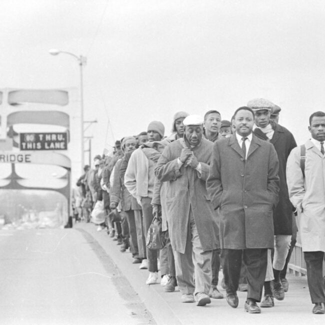 Signature image for sharing: John Lewis and many other civil rights protestors at the Edmund Pettis bridge at Selma, 1965. Black and White news photo in pub domain.