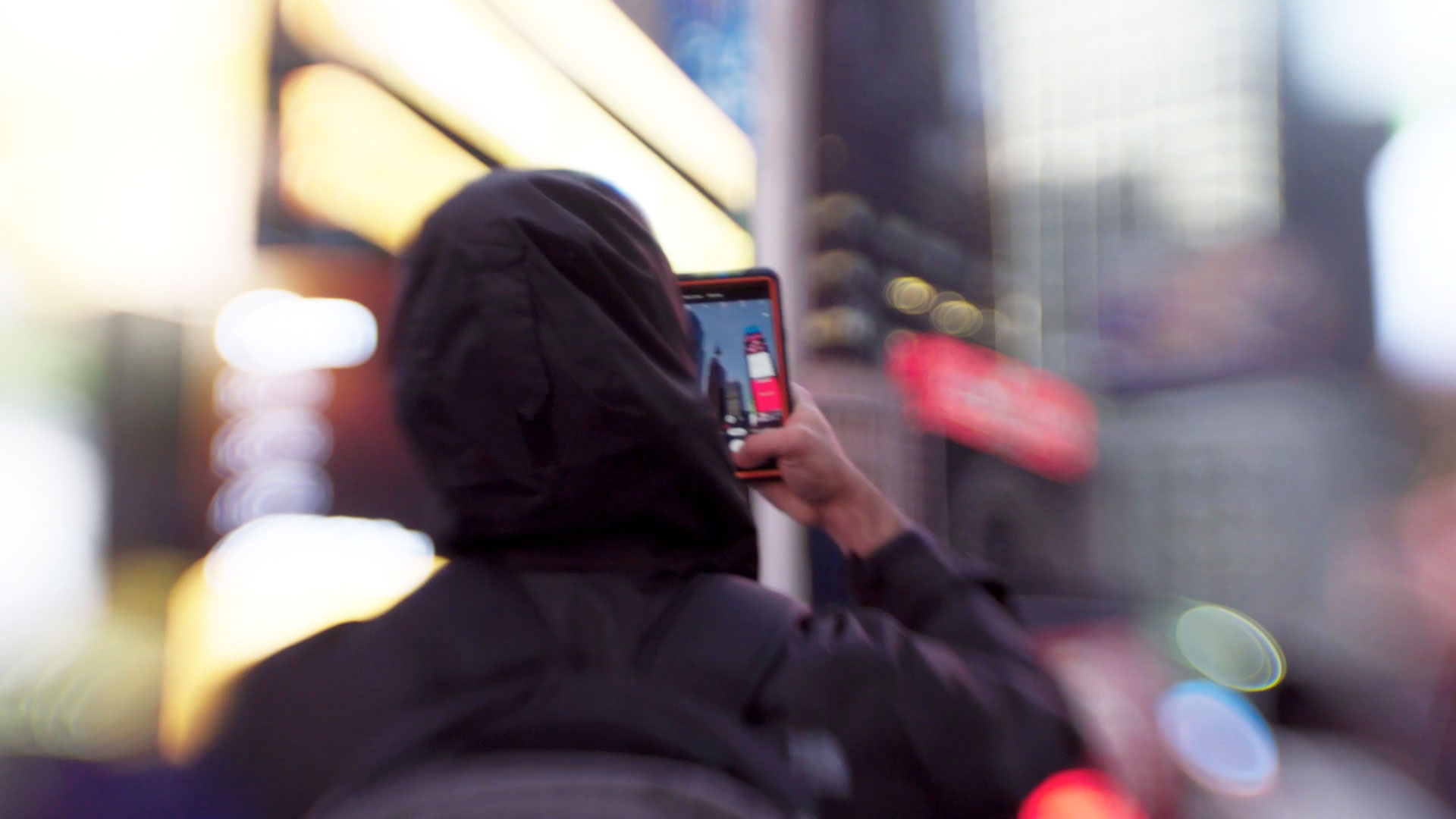 A person scanning their face on smartphone on city street, in a Still from Coded Bias, directed by Shalini Kantayya