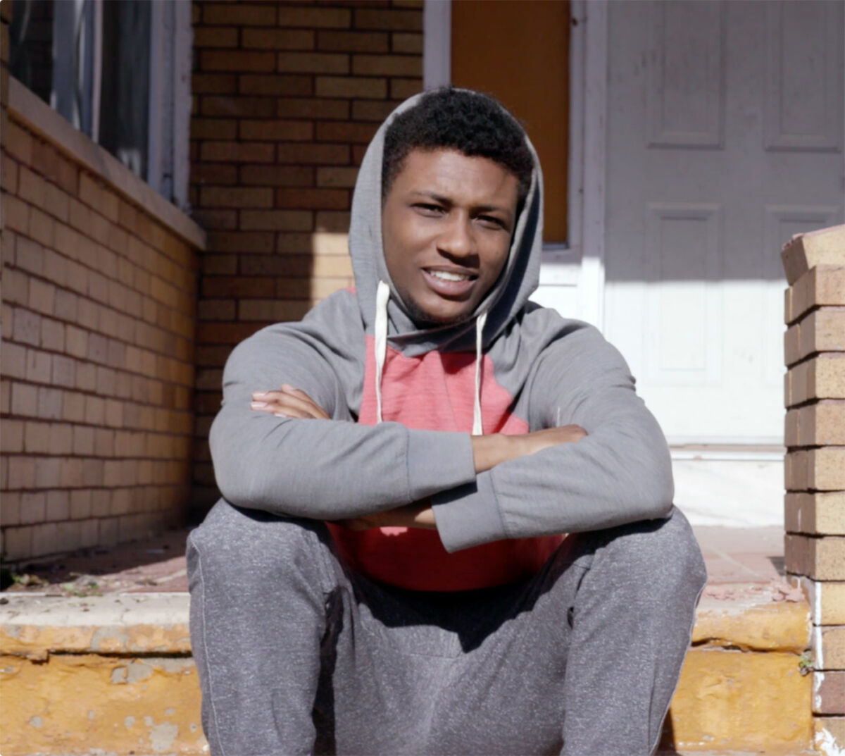 young man sits on the steps in Baltimore, in scene from Owned