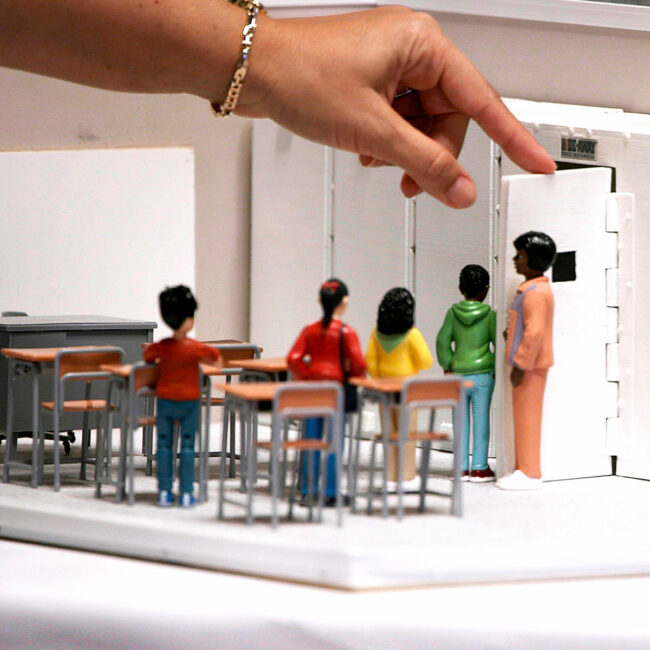 Model of a classroom safety drill, with figurines of teacher and students and a model of a safe room