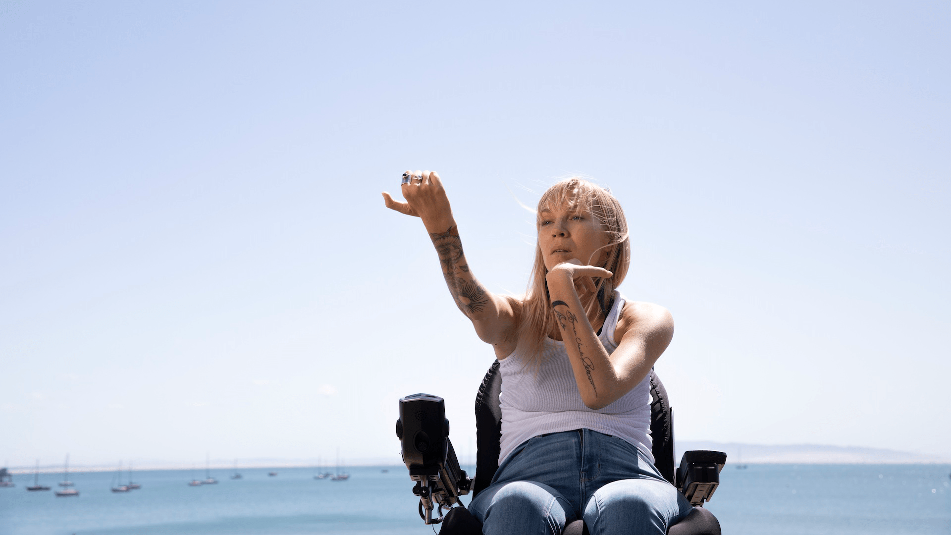 Kelsey Peterson, a woman i a wheelchair, at the beach, stretching her wrists