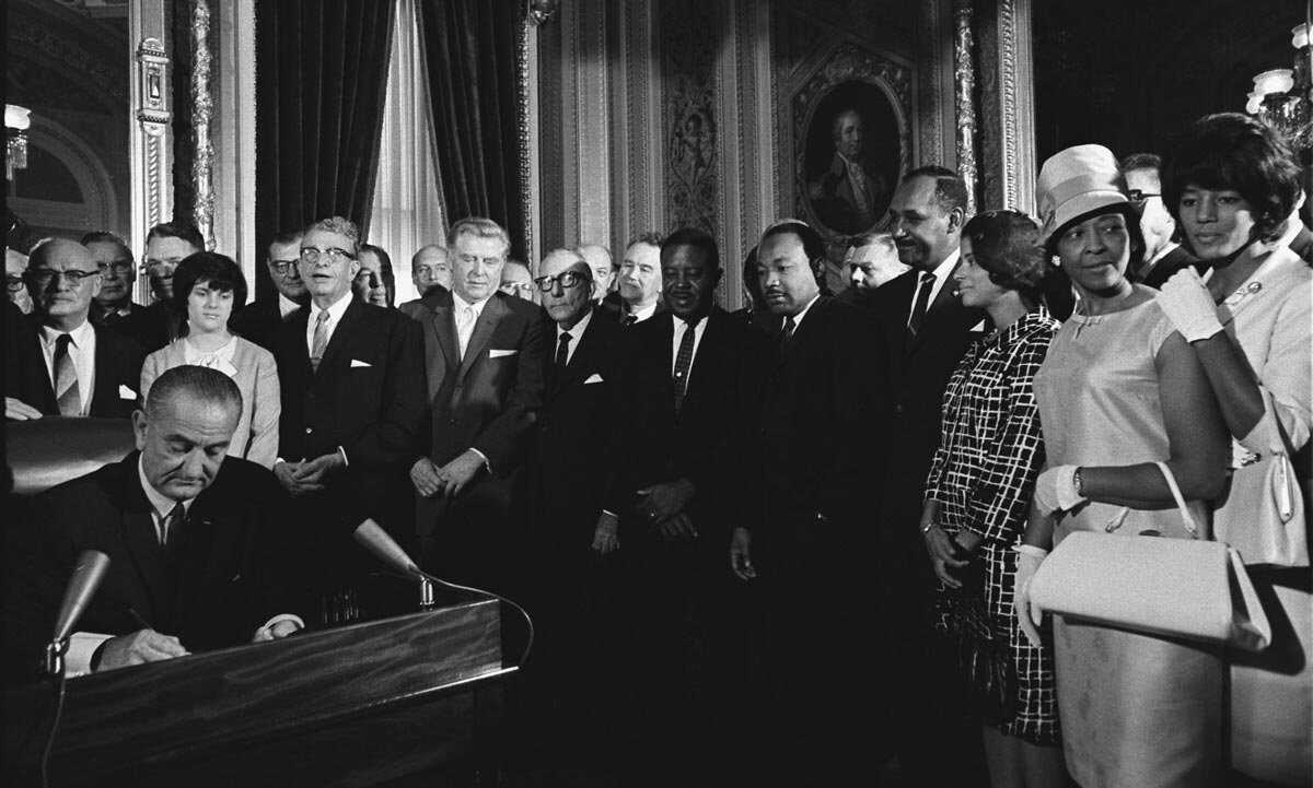 President Lyndon B. Johnson signs the Voting Rights Act as Martin Luther King Jr. and other civil rights leaders look on; President's Room, U.S. Capitol, Washington, DC. LBJ Library, photo by Yoichi Okamoto. LBJ-Civil-Rights.jpg