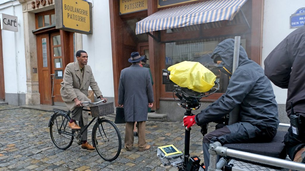 Parker Sawyers riding a bike for a scene in World on Fire, Season 1