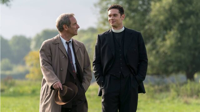 Geordie Keating and Will Davenport walking side-by-side in a lush green field in Grantchester