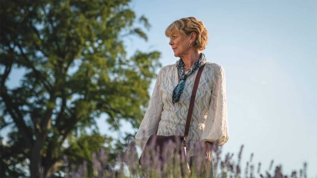 Samantha Bond as Judith Potts standing outdoors in The Marlow Murder Club