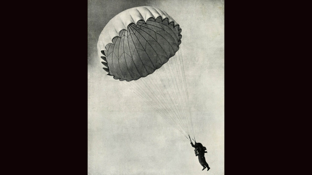 Black and white photo of WW2 airman using a parachute, 1941.