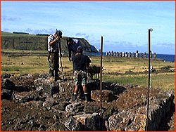 Photo of workmen on experiment ahu platform,
Tongariki in the background. Two of the workmen are standing on the pedestal, on which the
moai will stand. The third (black shirt) is standing on the platform, the
ahu, and the ramp up to the ahu leads to the lower left of the picture.