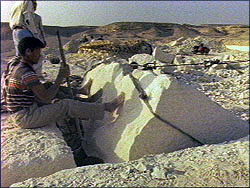 Man cutting stone in quarry with pick