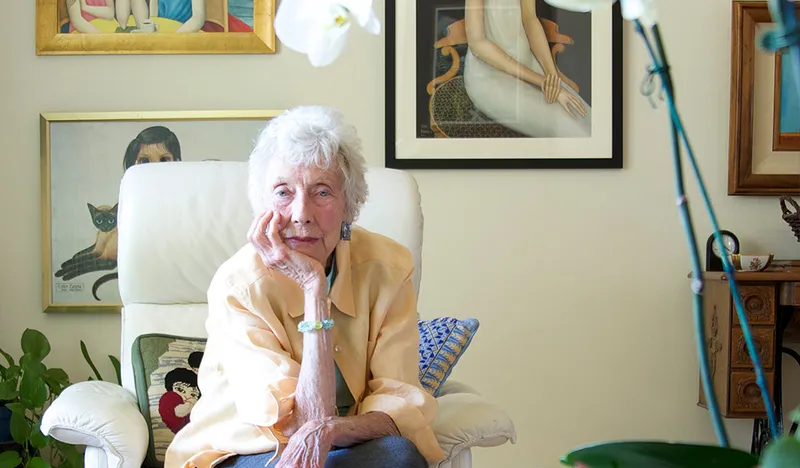 Margaret Keane seated with her artworks