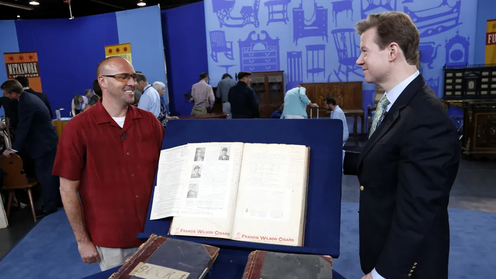 Appraiser Francis Wahlgren and guest in front of three hotel ledger books full of wanted posters